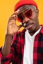 Closeup portrait of a stylish black African man in red retro glasses and a plaid shirt and hat in the studio Royalty Free Stock Photo