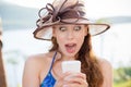 Closeup portrait surprised screaming young girl in hat looking at phone seeing news or photos with funny emotion on her face Royalty Free Stock Photo