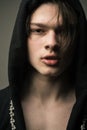 Closeup portrait of teenage boy wearing black hood. Young man with medium length hair and full lips singing rap, hip hop Royalty Free Stock Photo