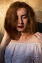 Closeup portrait of tender red haired girl in white dress posing