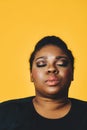 closeup portrait of a thoughtful beautiful young adult african american woman with eyes closed afro hairstyle on yellow Royalty Free Stock Photo