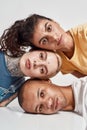 Closeup portrait of three diverse friends looking at camera, laying head on each other, posing isolated over light