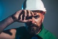 Closeup portrait of tired builder in construction helmet. Fatigued worker wipes sweat from forehead. Hard work at Royalty Free Stock Photo
