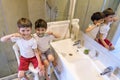 Closeup portrait of twins kids toddler boy brother in bathroom toilet washing face hands brushing teeth with toothbrush playing Royalty Free Stock Photo