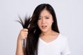 Closeup portrait of unhappy, frustrated, young woman holding her hair in hand, looking at her damage split ends. Beauty hairstyle Royalty Free Stock Photo