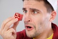 Closeup portrait unhappy, upset man holding small red gift Royalty Free Stock Photo