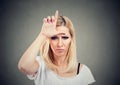 Portrait unhappy woman giving loser sign on forehead, looking at you with anger and hatred on face