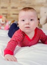 Closeup portrait view of one funny smiling cute little baby boy with blonde hair lying on bed with soft blanket looking forward Royalty Free Stock Photo