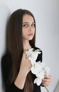 Closeup portrait on a white background of a girl with long dark hair and gray-green eyes who holds an orchid in her hands Royalty Free Stock Photo