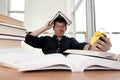 Closeup portrait of white man surrounded by tons of books, alarm clock, stressed from project deadline, study, exams