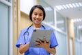 Closeup portrait of woman health worker wearing blue uniform In Hospital Corridor Using Digital Tablet Royalty Free Stock Photo
