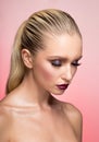 Closeup portrait of woman with splendid makeup and hair straightened and caught in the back, pink background