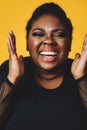 closeup portrait of a young adult black woman in laughing with mouth open toothy smile on yellow background Royalty Free Stock Photo