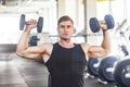 Closeup portrait of young adult man muscular built handsome athlete working out in a gym, sitting and holding two dumbbell with Royalty Free Stock Photo