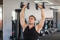 Closeup portrait of young adult man muscular built handsome athlete working out in a gym, sitting and holding two dumbbell with Royalty Free Stock Photo
