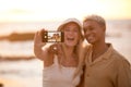 Closeup portrait of an young affectionate mixed race couple standing on the beach and smiling and taking a selfie with a Royalty Free Stock Photo