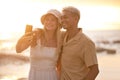 Closeup portrait of an young affectionate mixed race couple standing on the beach and smiling and taking a selfie with a Royalty Free Stock Photo