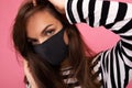 Closeup portrait of young attractive brunet woman in mediacal face mask isolated over background wall. Protection