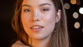 Closeup portrait of young attractive caucasian woman smiling and looking seductively at camera with bokeh lights on the Royalty Free Stock Photo