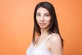 Closeup portrait of a young beautiful brunette woman holding looking at the camera against orange background Royalty Free Stock Photo