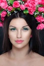 Closeup portrait of young beautiful brunette young woman with makeup and pink flowers in hair, over black background Royalty Free Stock Photo