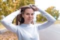 Closeup portrait, young beautiful girl on background of tree autumn leaves straightens her hair, casual clothes Royalty Free Stock Photo