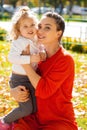 Closeup portrait of a young beautiful mother with little curly daughter in autumn park Royalty Free Stock Photo