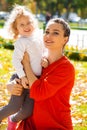 Closeup portrait of a young beautiful mother with little curly daughter in autumn park Royalty Free Stock Photo