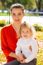 Closeup portrait of a young beautiful mother with little curly daughter in autumn park Royalty Free Stock Photo