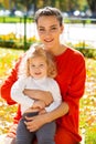 Closeup portrait of a young beautiful mother with little curly daughter in autumn park Royalty Free Stock Photo