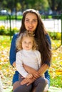 Closeup portrait of a young beautiful mother with little curly daughter in autumn park Royalty Free Stock Photo