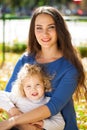 Closeup portrait of a young beautiful mother with little curly daughter in autumn park Royalty Free Stock Photo