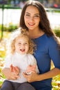 Closeup portrait of a young beautiful mother with little curly daughter in autumn park Royalty Free Stock Photo