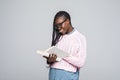 Portrait of a young beautiful woman is reading a book with glasses isolated over gray background Royalty Free Stock Photo