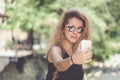 Closeup portrait of young beautiful woman in sunglasses with long blonde curly hair doing selfie photos Royalty Free Stock Photo