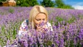 Closeup portrait of young blonde woman smelling lavender flowers on field Royalty Free Stock Photo