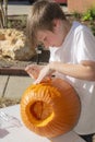 Portrait of a young handsome boy outside carving pumpkins Royalty Free Stock Photo