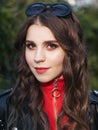 Closeup portrait of young brown-haired curly woman with trendy creative red makeup posing outdoors in bright sunlight. Pretty girl Royalty Free Stock Photo