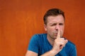 Closeup portrait of young caucasian man placing finger on lips as if to say, shh, be quiet Royalty Free Stock Photo