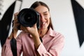 Closeup portrait of young female photographer taking photo, lady working at photostudio with lighting equipment