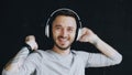 Closeup portrait of young funny man puts on headphones and crazy dancing while listen to music on black background Royalty Free Stock Photo