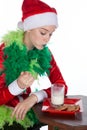 Closeup portrait of young girl wearing red santa clause hat mouthful of biscuit looking at milk
