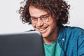 Closeup portrait of young happy businessman with curly hair, wearing round eyeglasses, working on his laptop in office. Royalty Free Stock Photo