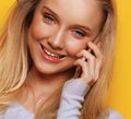 Portrait of young, happy woman talking on phone looking at camera, over yellow background Royalty Free Stock Photo
