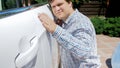 Closeup portrait of young man gently touching his new car door Royalty Free Stock Photo