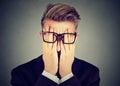 Closeup portrait young man in glasses covering face eyes with both hands Royalty Free Stock Photo