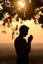 Closeup portrait young man praying against sunset Royalty Free Stock Photo