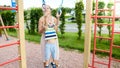 Closeup portrait of young mother helping and holding her little son hanging and swinging on sportrs rings at palyground Royalty Free Stock Photo