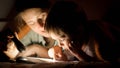 Closeup portrait of young mother holding flashlight while reading a book to her little son at night Royalty Free Stock Photo