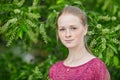 Closeup portrait of young natural beautiful redhead woman in fuchsia blouse posing against blossoming tree with blurred green foli Royalty Free Stock Photo